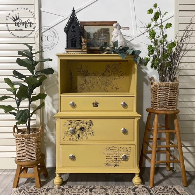 Light yellow painted tallboy dresser with floral accents and wooden stools with woven baskets