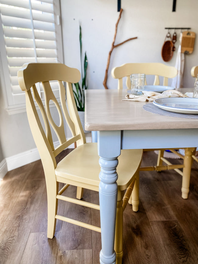 Light wood stained dining table top with light yellow chairs