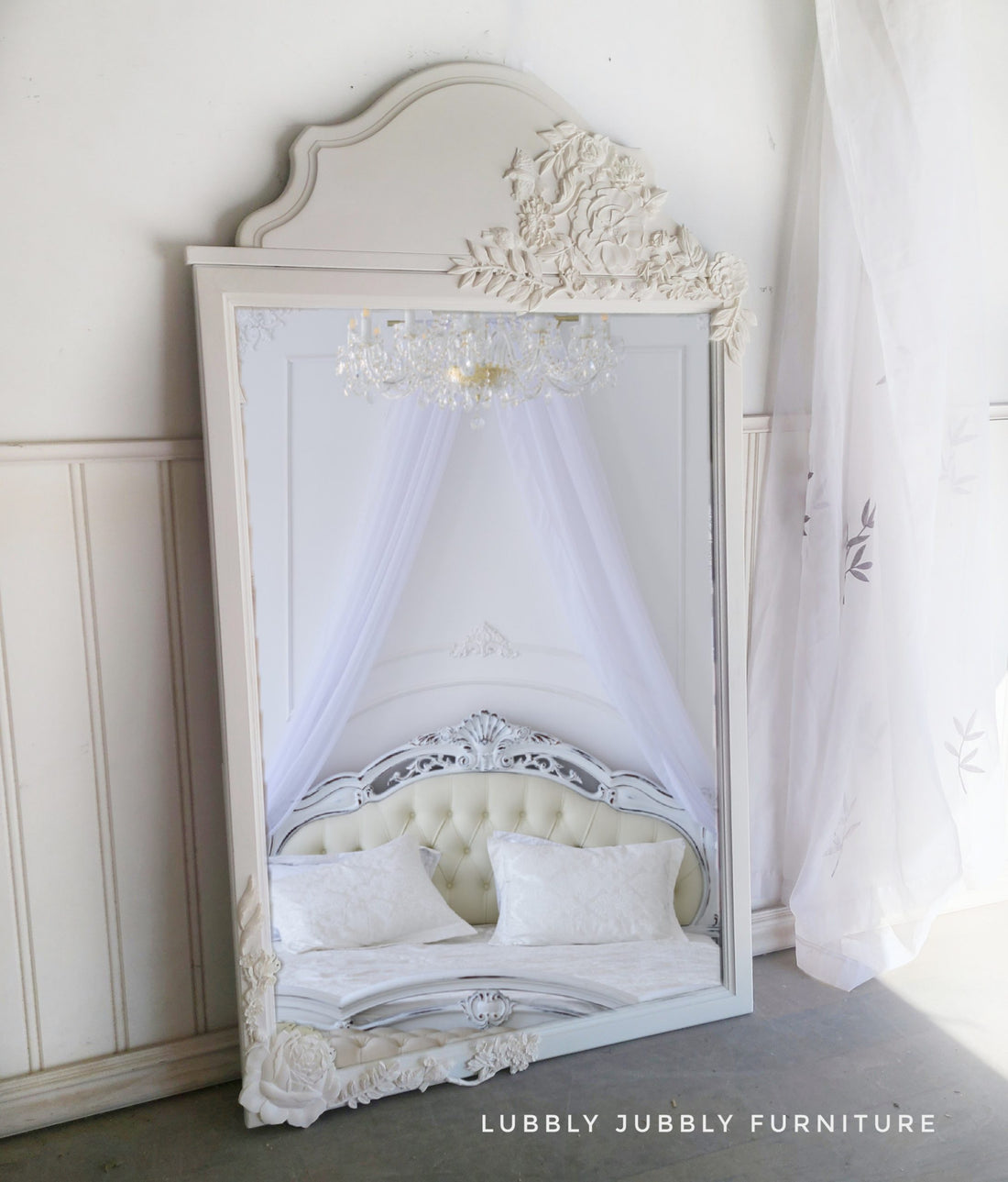 Ornately embossed white mirror frame with floral molds