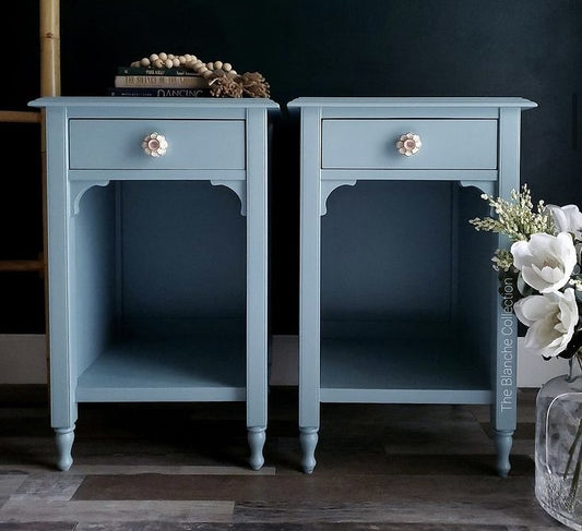 Two light blue painted nightstands against a black wall