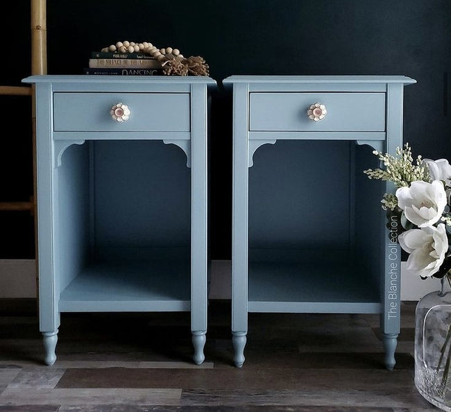 Two light blue painted nightstands against a black wall