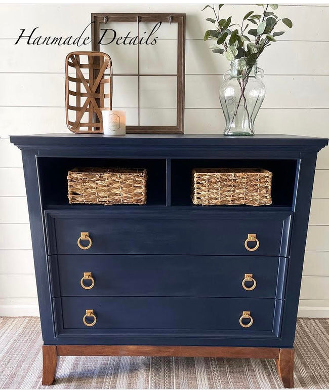 Navy blue dresser with woven baskets and gold circle hardware