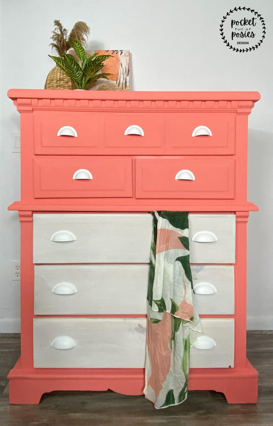 tall five drawer dresser in warm coral pink and light greige with silver cup pulls, blanket, potted plants, vintage books