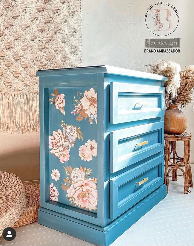 Three Drawer end table painted in deep ocean blue with floral transfer and gold hardware, potted feathers, macrame wall hanging, wooden stool