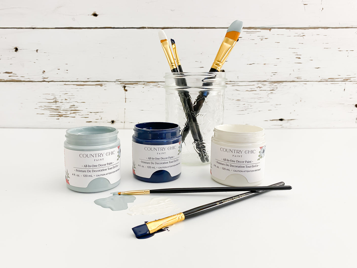 artist brushes dipped in paint with three paint jars