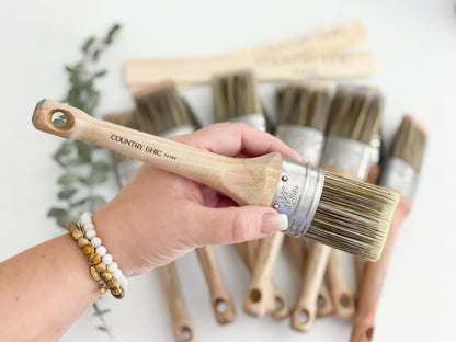 assorted oval paint brushes with stir sticks one paint brush held in hand